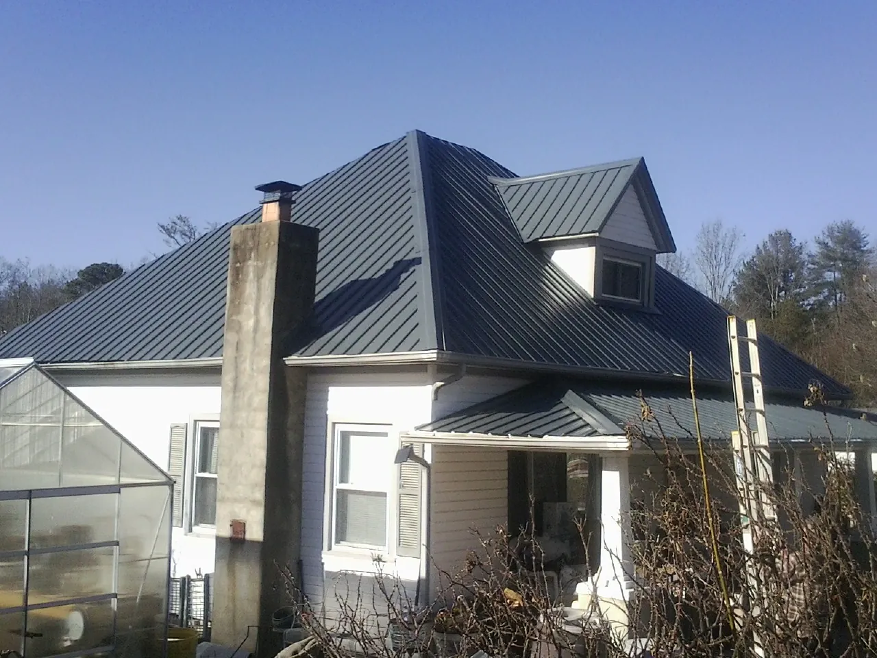 Dark blue standing seam metal roof on a white farmhouse with dormer — Slate & Tile Roof Repair by Roofing Brothers in Anita