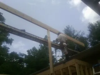 Carpenter setting a ridge beam over a new addition frame — Ice Dam Removal by Roofing Brothers in Anita