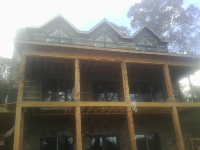 Dormers and porch framing on a large log home under construction — Roof Coating work by our crew in Anita