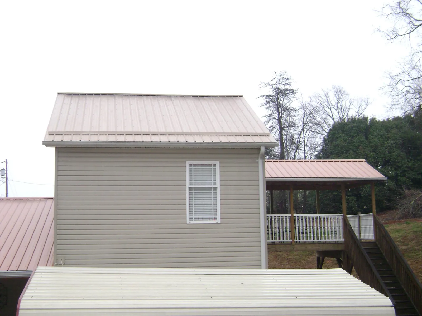 Tan metal roofs on a two story addition and attached porch, from a Roof Replacement job in Anita