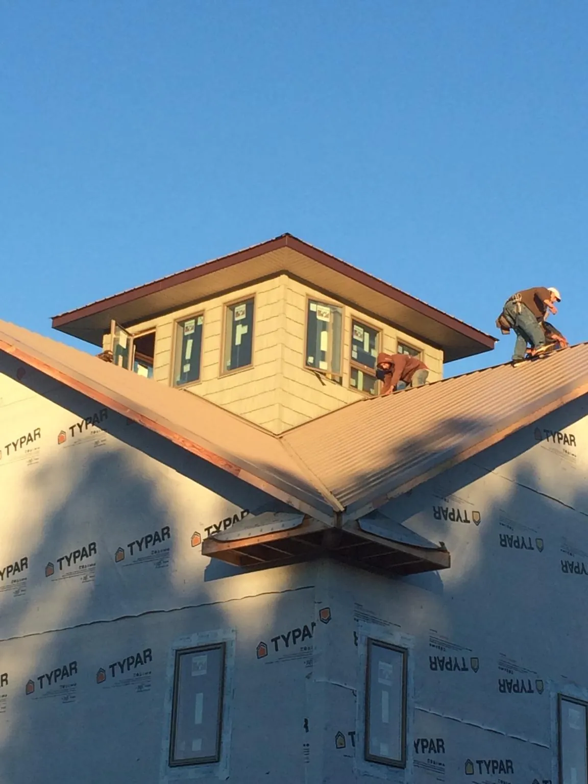 Roofers working around a rooftop cupola on a new metal roof at sunset — Roof Waterproofing in Anita by Roofing Brothers